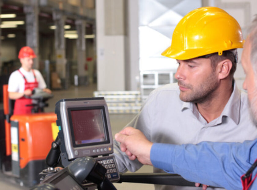 male inspector looking at screen with operator in warehouse